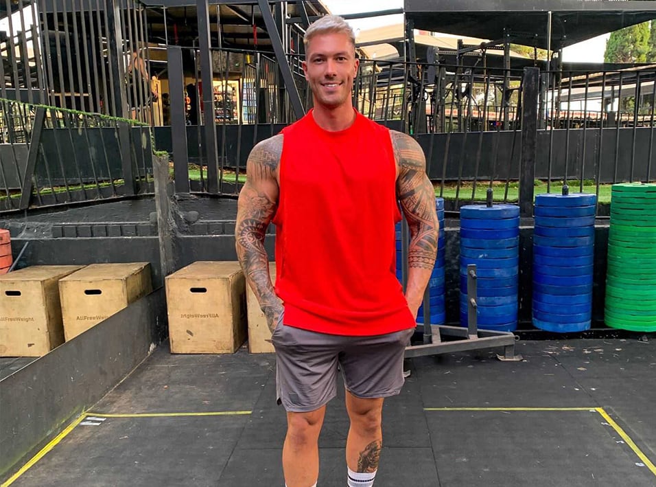 Adam with a red shirt posing in a gym